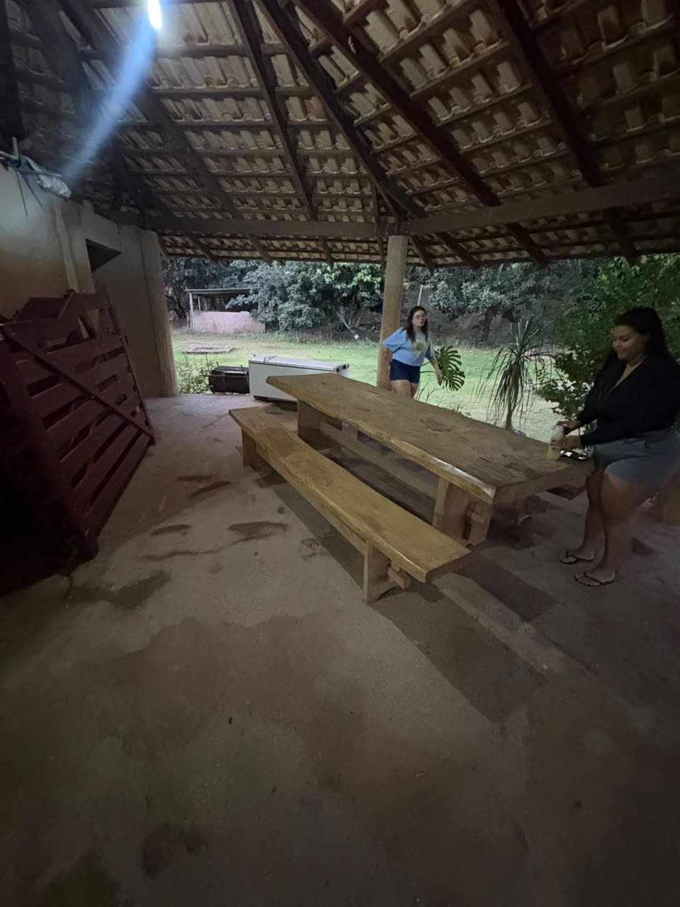 Mesa comprida de madeira sob a área coberta do sítio