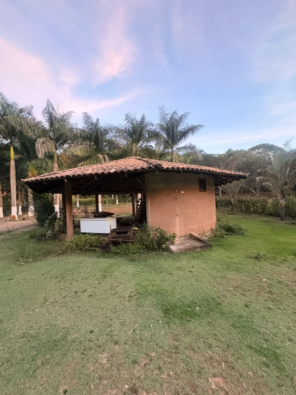 Quiosque de telha no gramado do sítio ao entardecer
